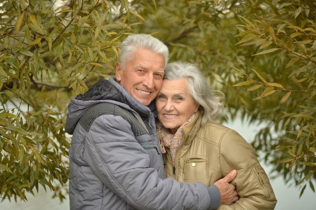 Casal feliz de idosos perto da água no parque de outono