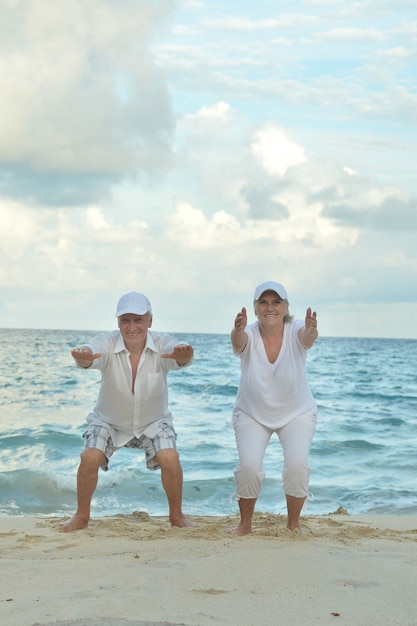 Casal feliz de idosos se exercitando no verão na praia