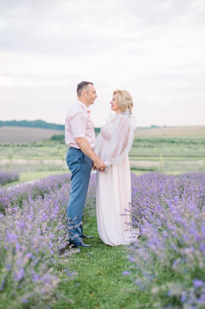 Casal feliz de meia-idade em um campo de lavanda roxa