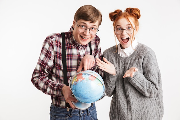 Casal feliz de nerds escolares segurando um globo terrestre