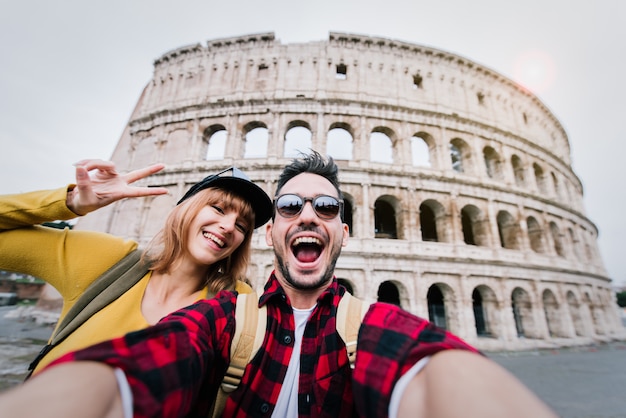 Casal feliz de turista se divertindo tomando uma selfie na frente do Coliseu, em Roma. As pessoas viajam Roma, Itália.