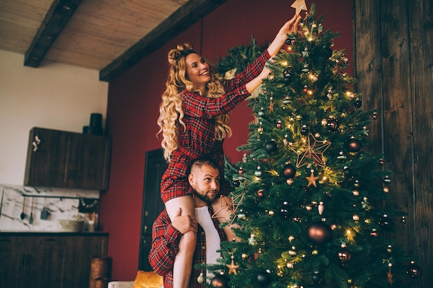 Casal feliz decorando a árvore de natal em casa