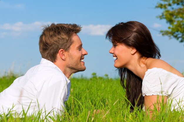 Casal feliz, deitado na grama, olhando um ao outro