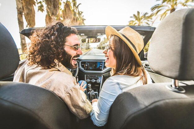 Casal feliz dirigindo carro conversível aproveitando as férias de verão