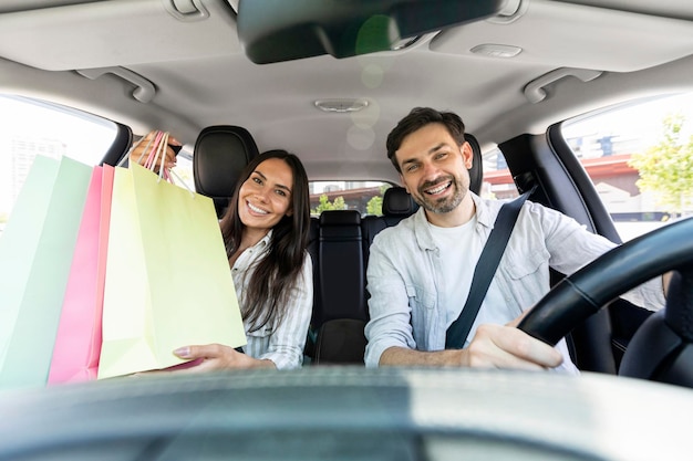 Casal feliz dirigindo para casa depois de fazer compras no shopping conversando sorrindo