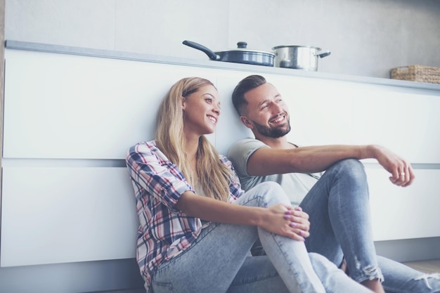 Casal feliz discutindo algo sentado no chão da cozinha