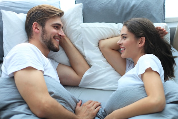 Casal feliz dormindo em uma cama confortável em casa.