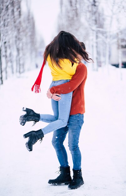 Casal feliz e animado apaixonado se diverte, dançando e se abraçando ao ar livre no parque da cidade de inverno enquanto comemora o dia de São Valentim