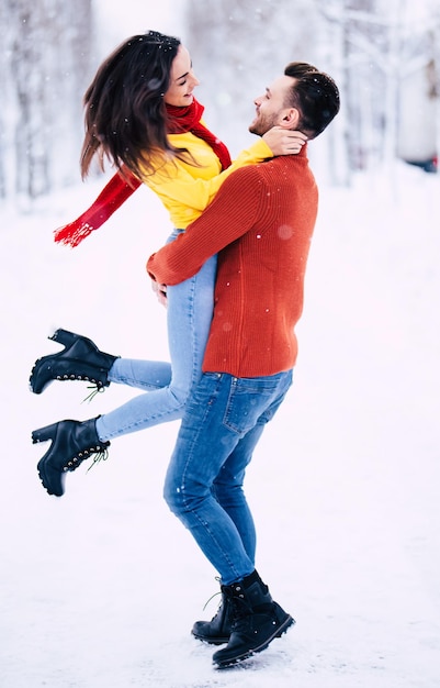 Casal feliz e animado apaixonado se diverte, dançando e se abraçando ao ar livre no parque da cidade de inverno enquanto comemora o dia de São Valentim