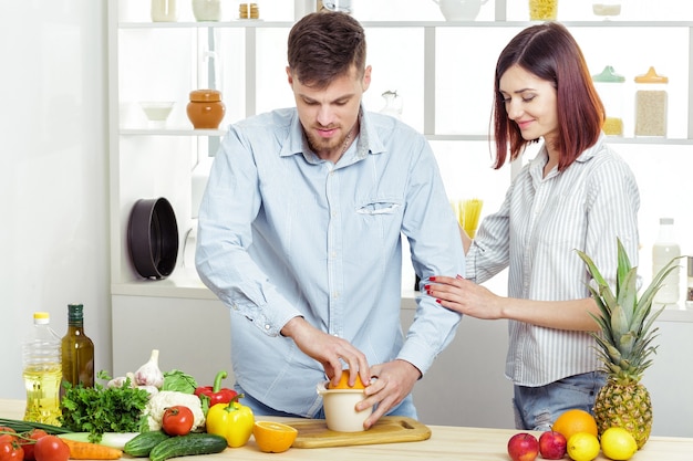 Casal feliz e apaixonado na cozinha fazendo um suco saudável de laranja fresca