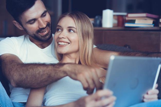 Casal feliz e apaixonado navegando em um tablet em casa