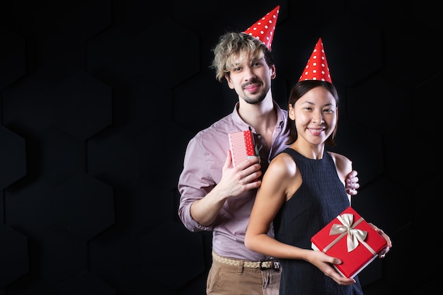 Casal feliz e diverso com presentes em um fundo preto. Conceito de férias.