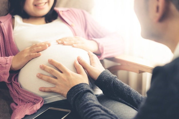 Casal feliz e grávida de marido e mulher. Esperando jovem segura bebê na barriga de grávida.