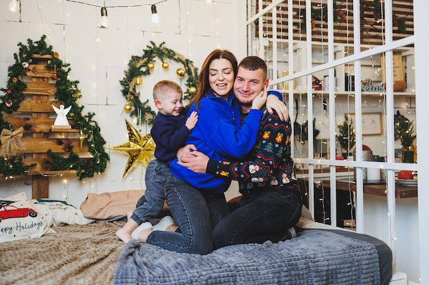 Casal feliz em casa com criança em locais de Ano Novo Clima festivo de Ano Novo no círculo familiar Decorações de Natal no quarto Ano Novo em casa Decorações de Natal em casa