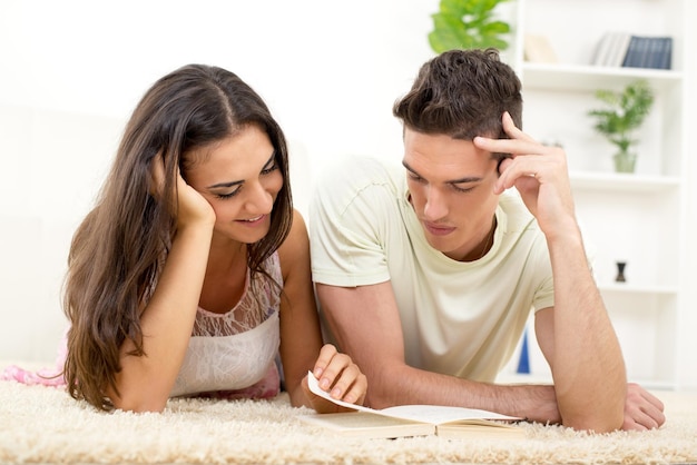 Casal feliz em casa lendo livro juntos no tapete