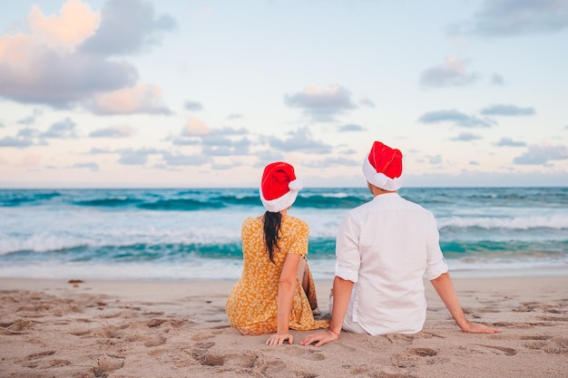 Casal feliz em chapéus de Papai Noel nas férias de praia de Natal