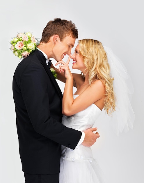 Casal feliz em comemoração no dia do casamento amor no casamento e felicidade de jovem e mulher na cerimônia juntos Noiva e noivo em fundo branco as pessoas sorriem com flores de buquê