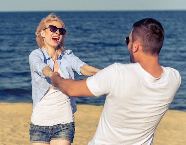 Casal feliz em óculos de sol está de mãos dadas.