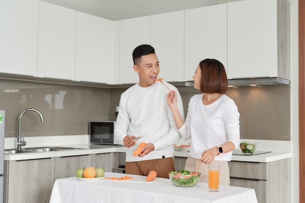 Casal feliz em pé na cozinha de casa preparando um jantar gostoso no primeiro namoro