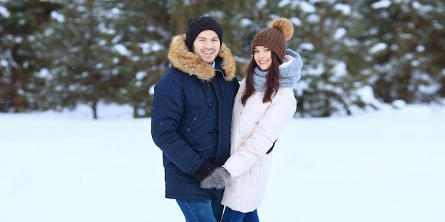 Casal feliz em pé na floresta de neve de inverno