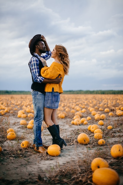 Casal feliz em pé no campo de abóboras