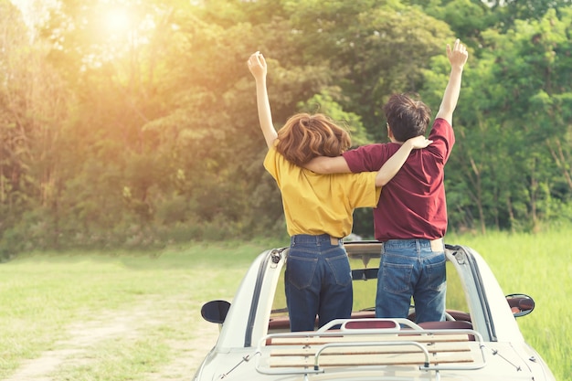 Casal feliz em viagem de carro ao pôr do sol.