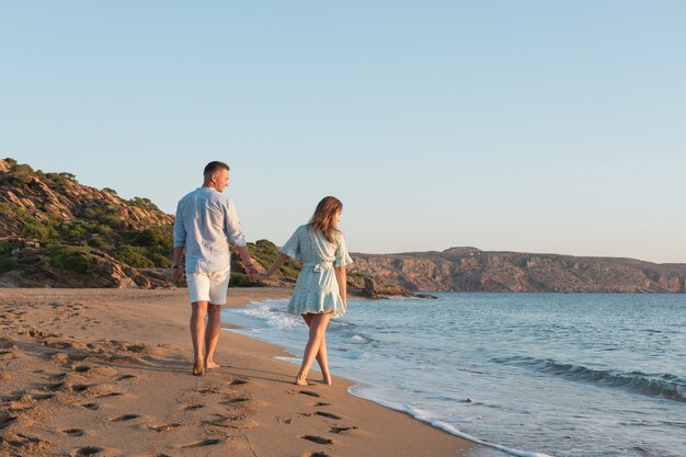 casal feliz está caminhando na praia durante o pôr do sol ou nascer do sol