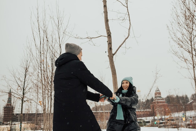 Casal feliz está circulando no parque de inverno nevado