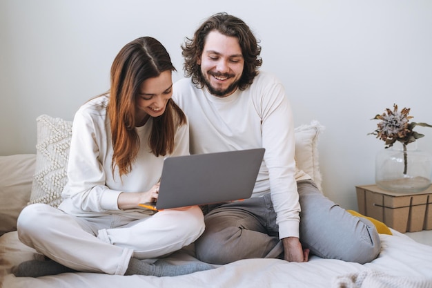 Casal feliz família jovem usando laptop na cama em casa