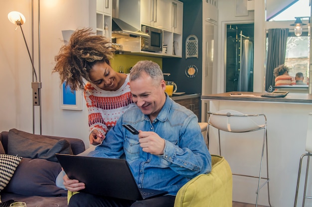 Casal feliz fazendo compras on-line com cartão de crédito e laptop. Casal gastando dinheiro online na internet.