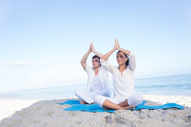 Casal feliz fazendo yoga ao lado da água