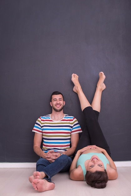 casal feliz grávida relaxando na frente do quadro preto no chão em casa