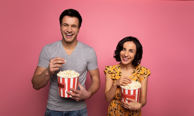 Casal feliz. homem e mulher apaixonados, que estão rindo, enquanto comem pipoca e assistem filmes.