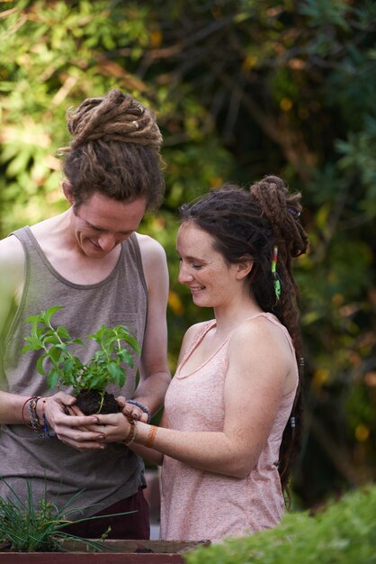 Foto casal feliz homem e mulher com plantas no quintal colheita e sustentabilidade de ervas para o crescimento pessoas trabalhando e cuidando do jardim juntos com sorriso namoro e ligação no relacionamento