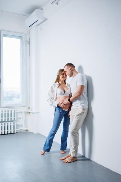 Casal feliz homem e mulher grávida em fundo branco no estúdio uma mulher grávida e seu marido Um casal apaixonado