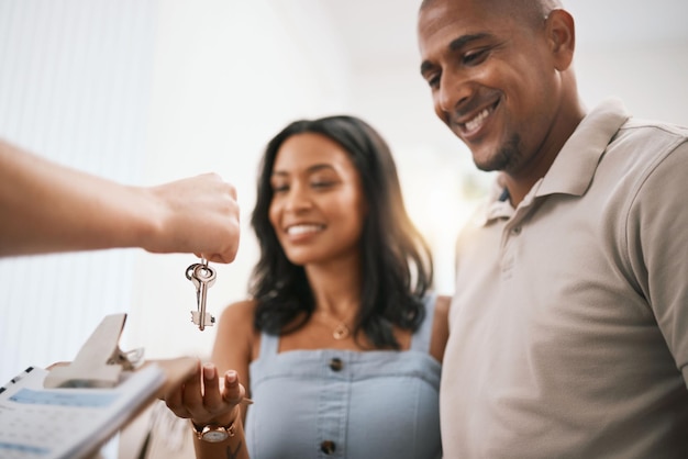 Foto casal feliz imobiliário e proprietário com chaves do corretor de imóveis para comprar empréstimo hipotecário ou investimento homem e mulher com sorriso para chave para mudança de casa ou venda em casa nova e papelada