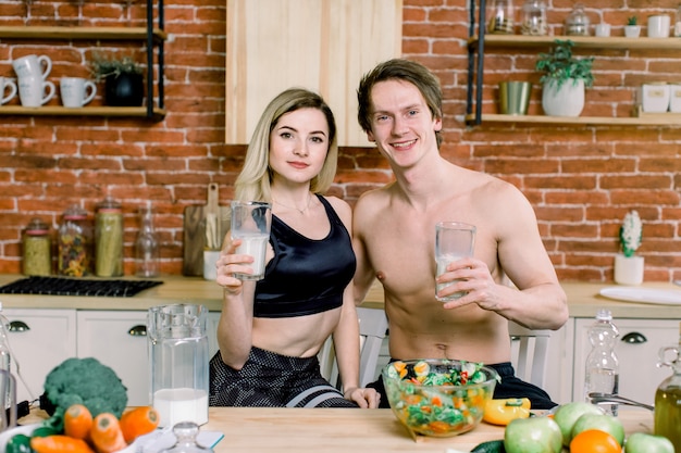 Casal feliz juntos a fazer o jantar e a beber leite na sua cozinha loft