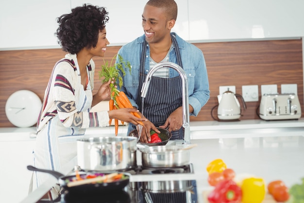 Casal feliz lavar legumes na cozinha