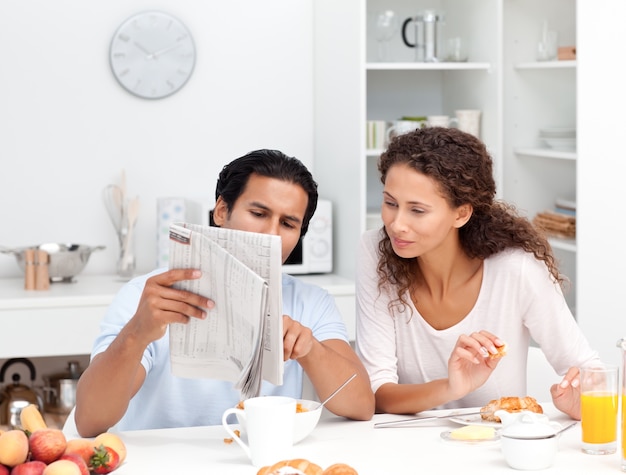 Casal feliz lendo o jornal juntos durante o café da manhã