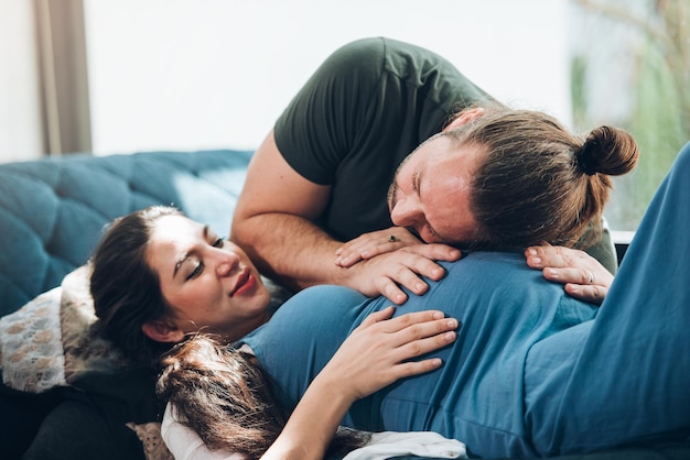 Foto casal feliz mulher grávida e marido ficam em casa na sala casal feliz cuidando juntos