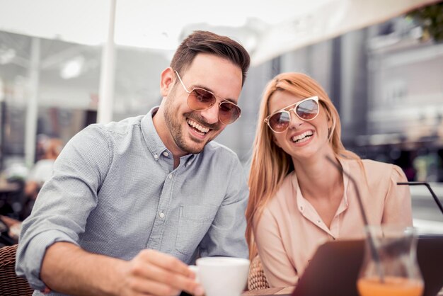 Casal feliz na cafeteria olhando para laptop