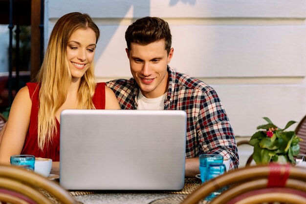 Casal feliz na cafeteria usando o laptop. Conceito de estilo de vida real.