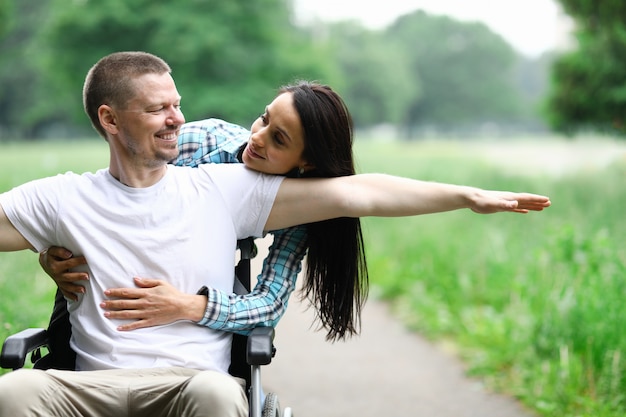 Casal feliz na caminhada no parque de cadeira de rodas com deficiência