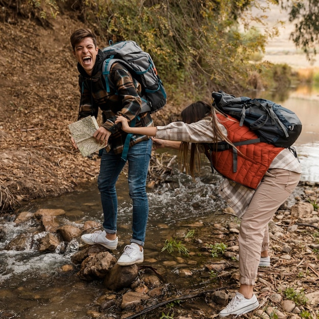 Foto casal feliz na garota da floresta tropeçou em uma pedra