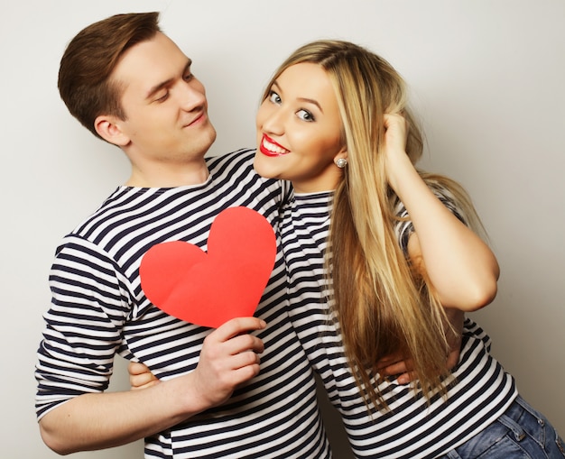 Casal feliz no amor segurando coração vermelho.