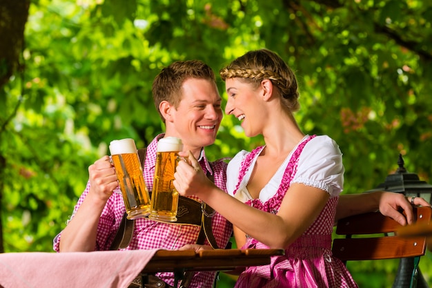 Casal feliz no jardim de cerveja bebendo cerveja