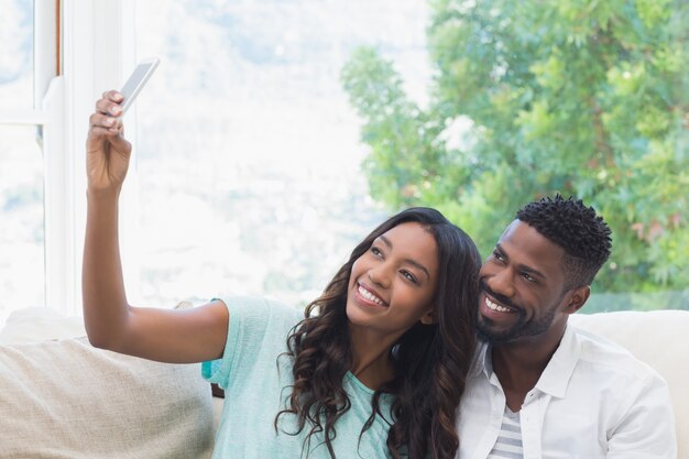 Casal feliz no sofá tendo selfie