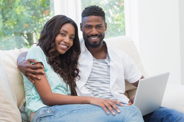 Casal feliz no sofá usando laptop