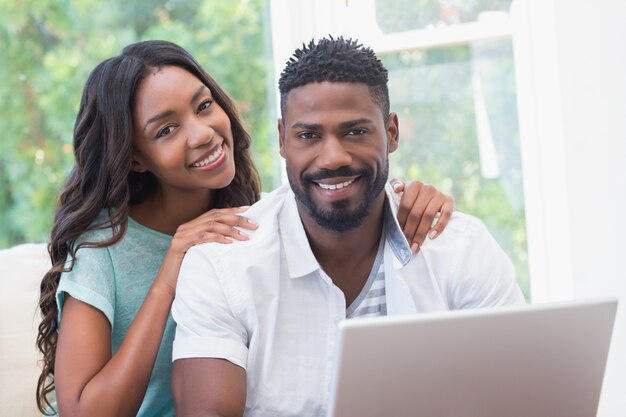 Casal feliz no sofá usando laptop