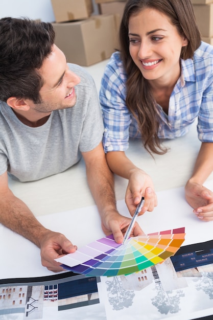 Casal feliz olhando um quadro de cores para decorar sua casa